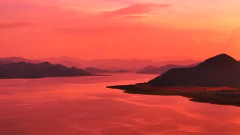 Aerial view of glowing red sunset sky over river and mountain silhouettes Stock Footage 316523219