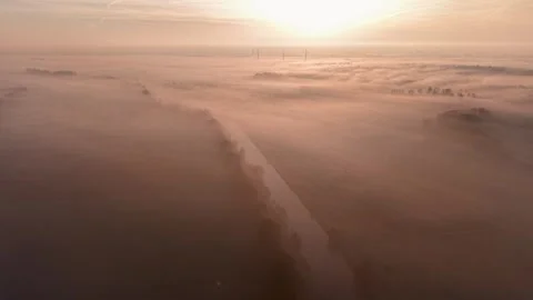 Aerial view of a golden sunrise over a river shrouded in thick morning fog. Vídeo Stock 332739853