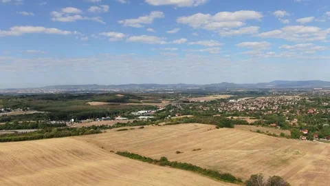 Aerial View of Golden Wheat Fields and Small Village with Mountains in Backgroun 動画素材 337239389