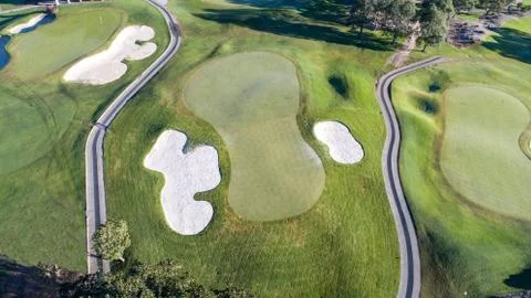 Aerial view of golf course green with flag, bunkers and golf cart pathways Stock Photos