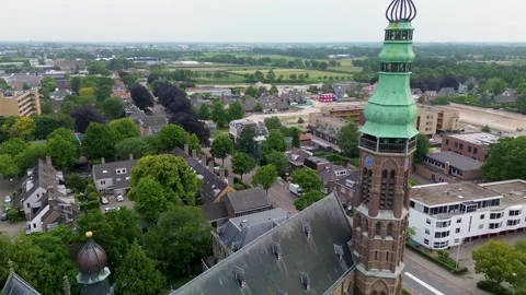 Aerial view of a Gothic style church with a green spire, surrounded by trees Stockbeeldmateriaal 317542653