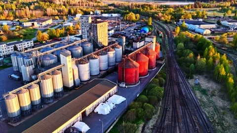 Aerial view of a grain elevator and silo complex at sunset with railroad tracks Stock Footage 337792091