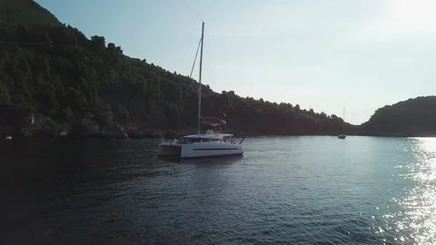 Aerial view, grazing flight approaching a Sailboat in a lonely bay at sunrise Stock Footage 96371404