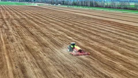 Aerial View of Green Claas Tractor With Seed Drill Sowing Vast Plowed Field in Stock Footage 334125633