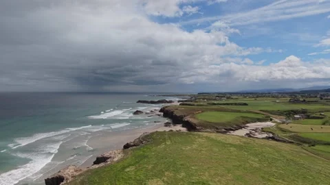 Aerial view of a green coast under passing storm clouds Vídeos de archivo 343325686