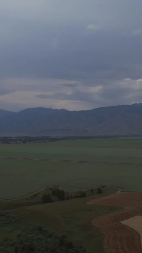Aerial view of green fields and mountains near Zamulta, Altai under storm clouds Stock Footage 335660889