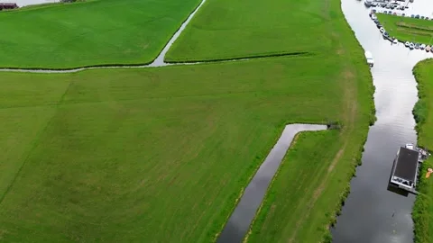 Aerial view of green fields divided by winding canals, with a small docked 库存影片 314787482