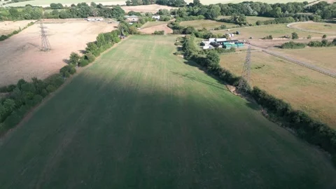 Aerial view of green fields, trees, power lines, and farm buildings under a.. Stock Footage 340475280