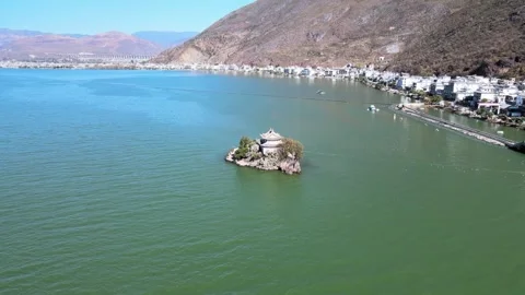 Aerial view of green lake surface small lake center island surrounding villages Stock Footage 337923725