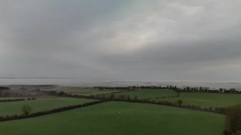 Aerial View of Green Patchwork Farmland Under Overcast Sky Stock Footage 332569072