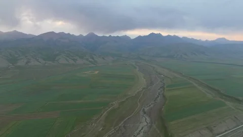 Aerial view of a green valley with fields and a riverbed at dusk, Kyrgyzstan Stock Footage 347241024