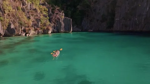 Aerial view of group of girlfriends in a transparent kayak paddling on the sea Stock Footage 282518853