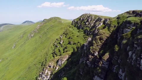 Aerial view of a group of hikers standing on top of a rocky mountain peak. Lush Stock Footage 344731100