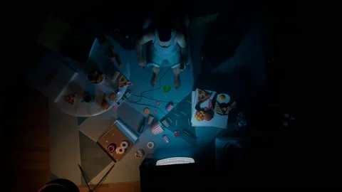 Aerial view for guy in the darkness watching tv surrounded by snacks and drinks Stock Footage 133435434