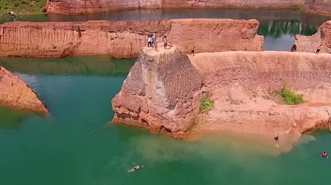 Aerial View of Guy Looking Then Jumping Off Cliff Into Lake with Buddy 库存影片 55296484