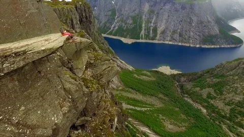 Aerial view. Guy sits on the edge of a huge rock against the backdrop of a 스톡 동영상 82310155