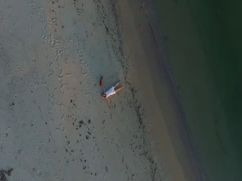 Aerial view of happy woman who lies on the surf line Stock Footage