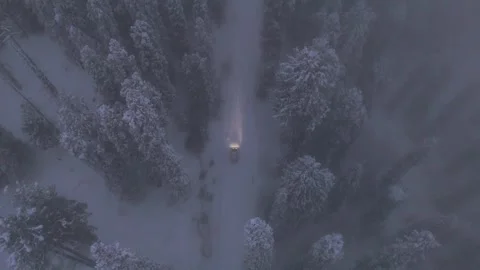 Aerial view of headlights cutting through snow mist on Gulmarg road. Stock Footage 311947351