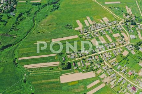 Aerial view from the height of the village with houses and streets, plowed fi Stock Photos