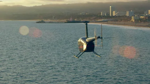 Aerial view of helicopter flying over ocean shoreline near pier during beautiful Stock Footage 199461272