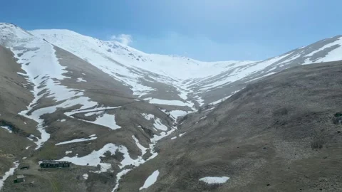 Aerial view of high mountains covered with snow against a blue sky Drone footage Stock Footage 257419358