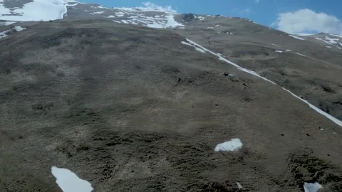 Aerial view of high mountains covered with snow against a blue sky Drone footage Stock Footage 257421048