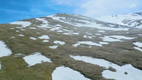 Aerial view of high mountains covered with snow against a blue sky Drone footage Stock Footage 257448120