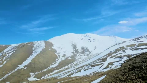 Aerial view of high mountains covered with snow against a blue sky Drone footage Stock Footage 257450776