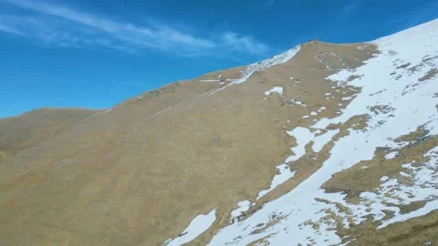 Aerial view of high mountains covered with snow against a blue sky Drone footage Stock Footage 257456004