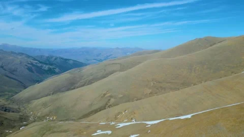 Aerial view of high mountains covered with snow against a blue sky Drone footage Stock Footage 257456600