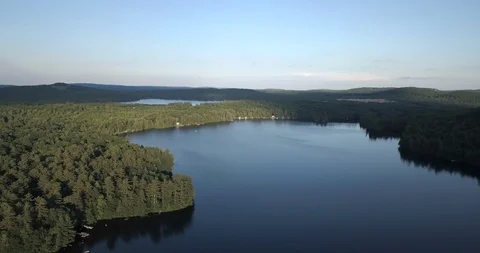 Aerial view high over blue lake in the forest with speed boat and waterskier Stock Footage 111509722
