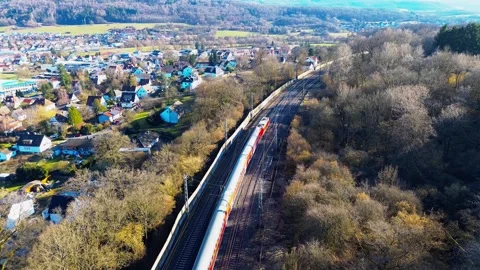 Aerial view of high speed passenger train passing suburban town and forest in Stock Footage 333588014