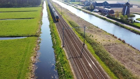 Aerial view of high speed train passing by traditional Dutch windmill Stock Footage 115366974
