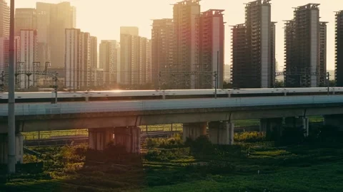 Aerial view of a high speed train travels on an elevated track past tall Stock Footage 340939848