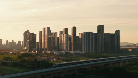 Aerial view of a high speed train travels on an elevated track past tall Stock Footage 340939983