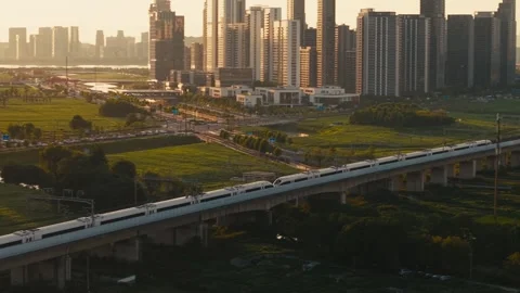 Aerial view of a high speed train travels on an elevated track past tall Stock Footage 340940011