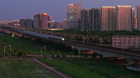 Aerial view of a high speed train travels on an elevated track past tall Stock Footage 341642837
