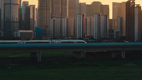 Aerial view of a high speed train travels on an elevated track past tall Stock-Footage 345243138