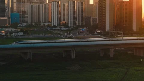 Aerial view of a high speed train travels on an elevated track past tall Stock-Footage 345243233