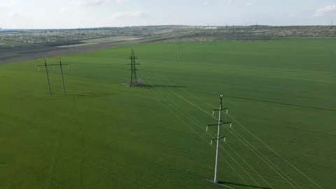 Aerial view of High voltage lines and power pylons in a flat and green Stock Footage 153816557