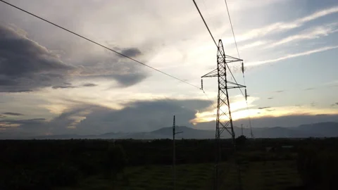 Aerial view of high voltage pylons and wires in the sky at sunset in countryside 動画素材 218354432