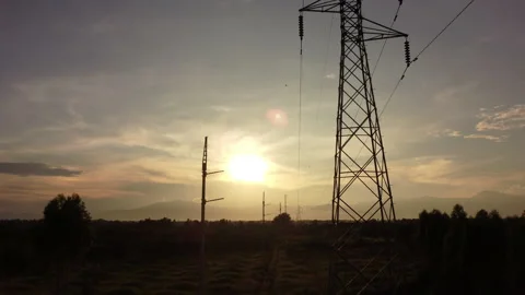 Aerial view of high voltage pylons and wires in the sky at sunset in countryside Vídeos de archivo 218413634