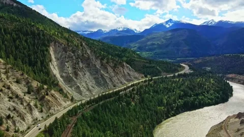 Aerial view of highway and river winding through mountain canyon in daylight Stock Footage 343543259