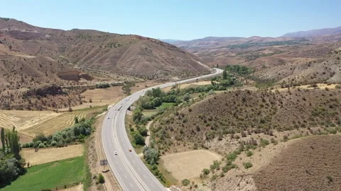 Aerial view of highway between hills and farmland Stock Footage 294091998