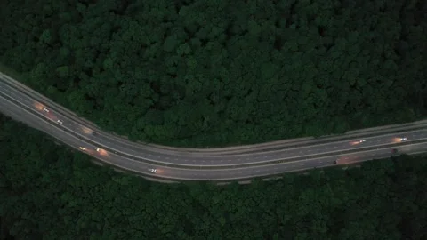 Aerial view of a highway curve through a forest at dusk Stock Footage 338013674