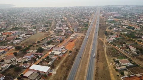 Aerial view of a highway cutting through a city with buildings and vehicles on Stock Footage 307886708