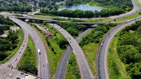 Aerial view of highway interchange with moving traffic, green trees... Vídeo Stock 340657890