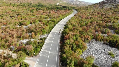 Aerial View Of Highway In Mountain Area With Two Cyclists Riding On It Stock Footage 129637698