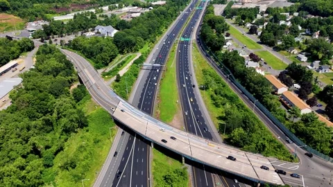 Aerial view of highway overpass with traffic moving through green suburban... Stock-Footage 340657903