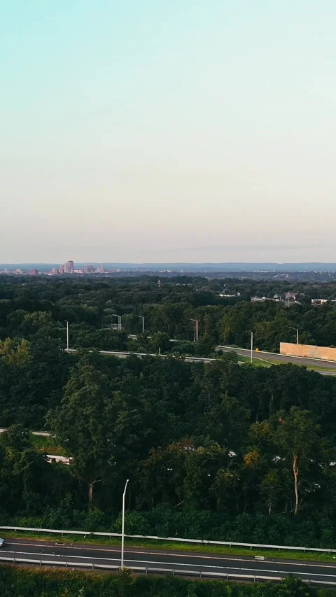 Aerial view of highway passing through dense forest with distant... Vídeo Stock 344332594